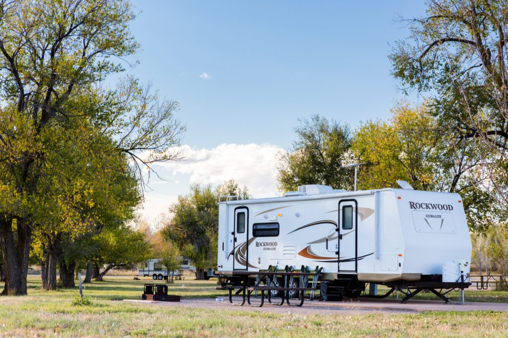 A white rv parked in the grass near trees.
