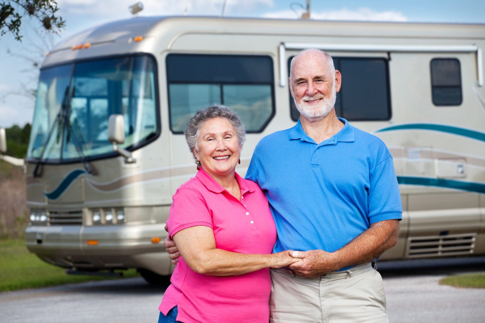 A man and woman standing in front of a silver rv.