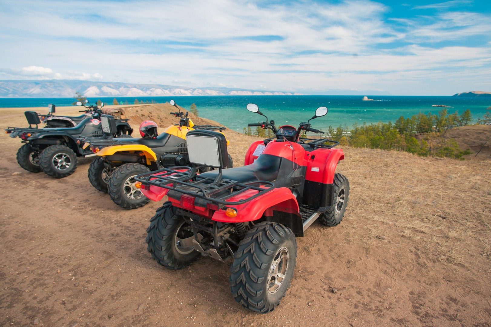 Two atvs parked on the beach near a body of water.