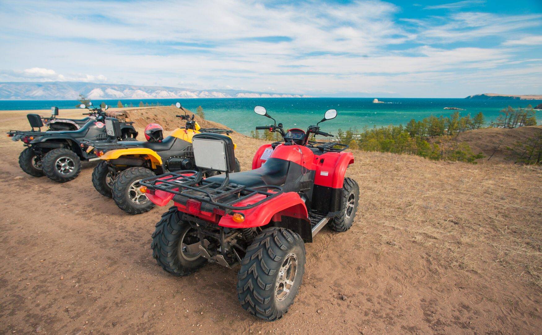 Two atvs parked on the beach near a body of water.
